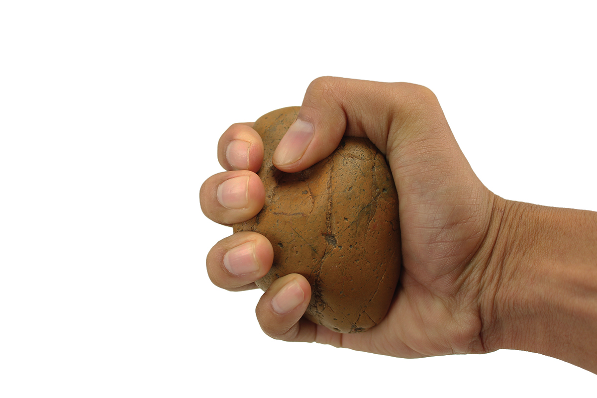 Hand squeezing stress ball, showcasing grip strength exercise on a white background.