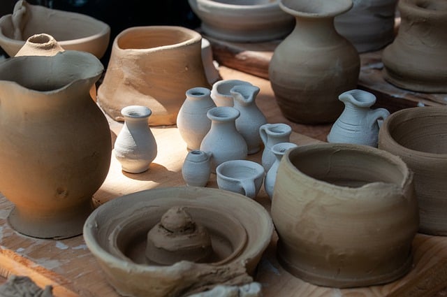 Handmade clay pottery in various shapes and sizes displayed on a wooden table in natural light.