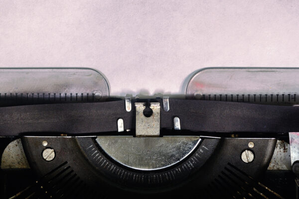 Close-up of vintage typewriter with blank paper, ready for writing.