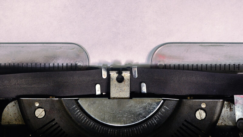 Close-up of vintage typewriter with blank paper, ready for writing.