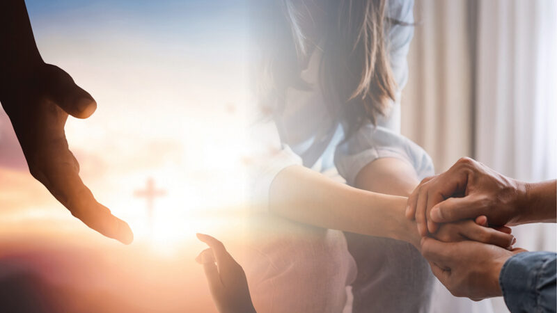 Hands reaching with a cross in the background, symbolizing hope and support in faith.