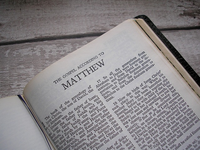 Open Bible displaying the Gospel according to Matthew on a wooden table.