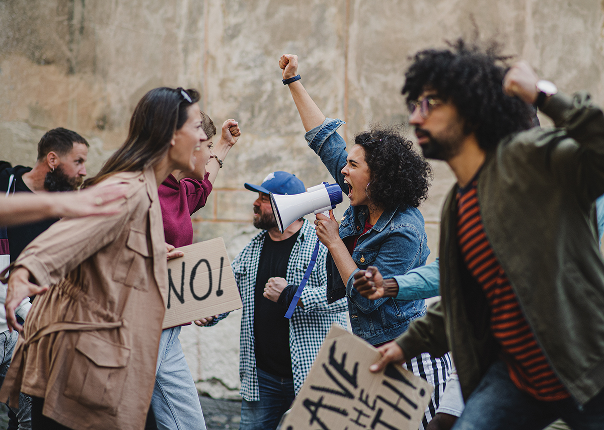 Protesters shouting with signs and megaphone in a passionate demonstration for change.