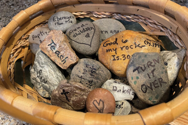 Basket of engraved gratitude stones with motivational words and Bible verses, inspiring reflection and mindfulness.