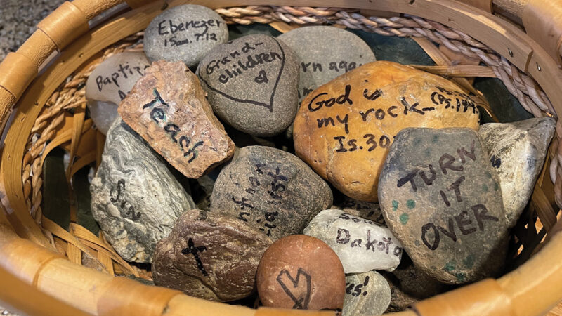 Basket of engraved gratitude stones with motivational words and Bible verses, inspiring reflection and mindfulness.