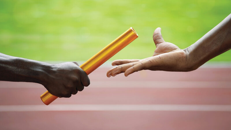 Two men passing golden baton in stadium