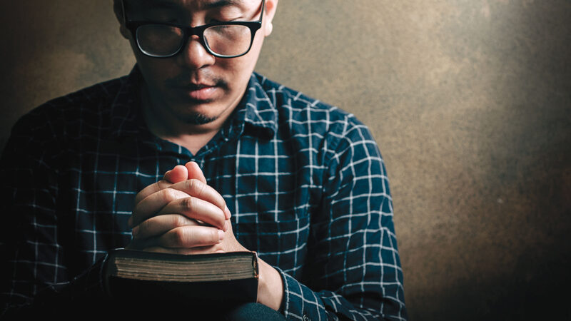 Christian life crisis prayer to god. Man Pray for god blessing to wishing have a better life. man hands praying to god with the bible. believe in goodness. Holding hands in prayer, eyes closed.