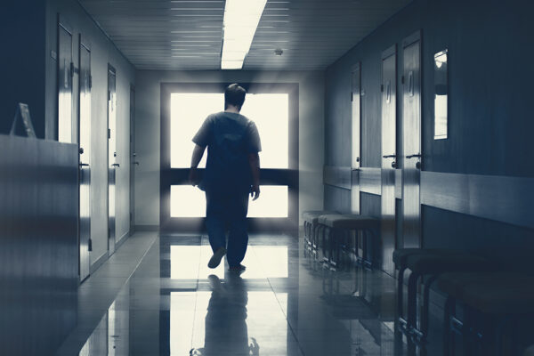 In the Hospital Elderly Pensioner Man Walks down the Hallway with Light in the End. Clean Modern Medical Facility. Life after Death, Door to Heaven Concept.