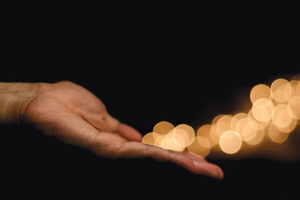 The hand releases yellow round shape bokeh light on black background.