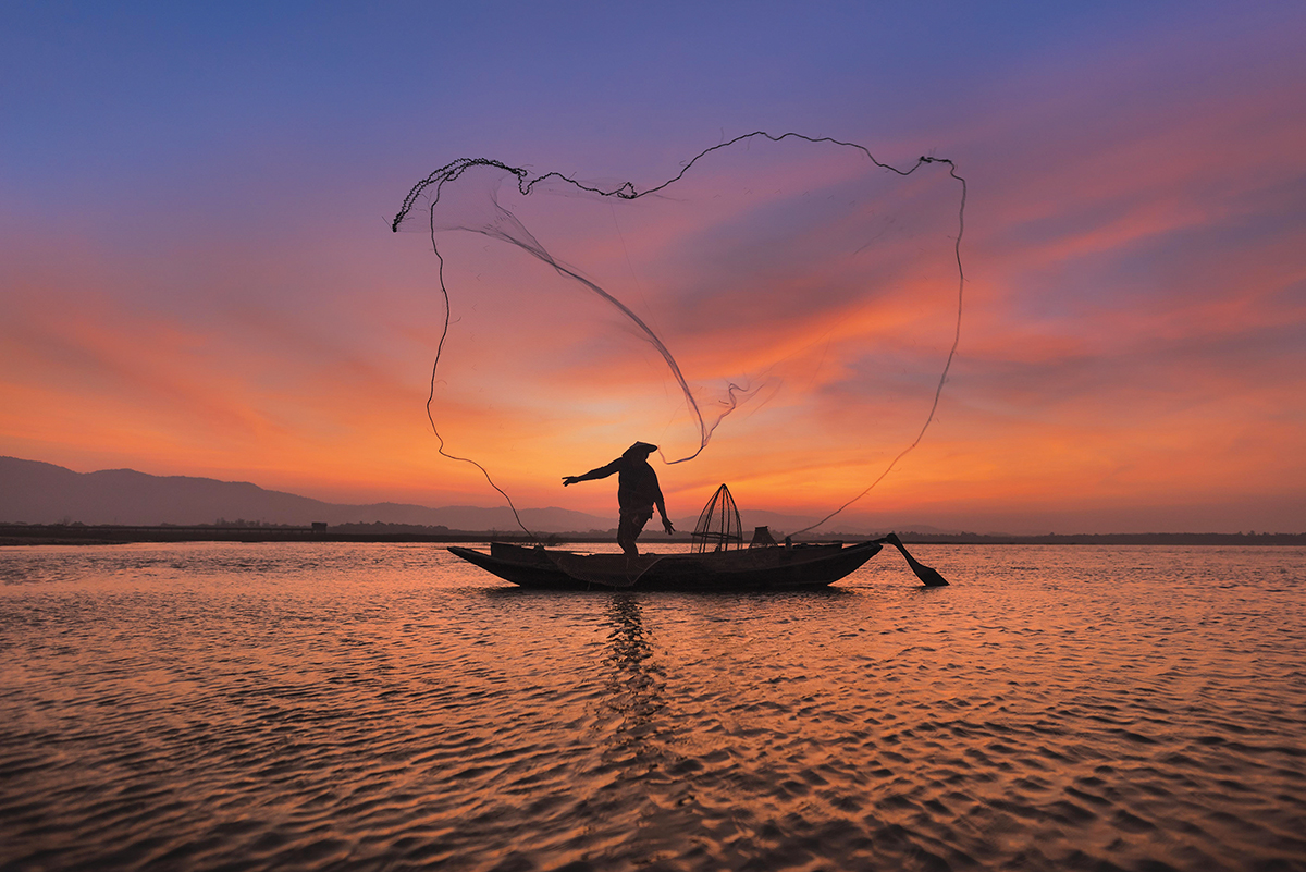 Asian Fisherman With His Wooden Boat In Nature River At The Early Morning Before Sunrise