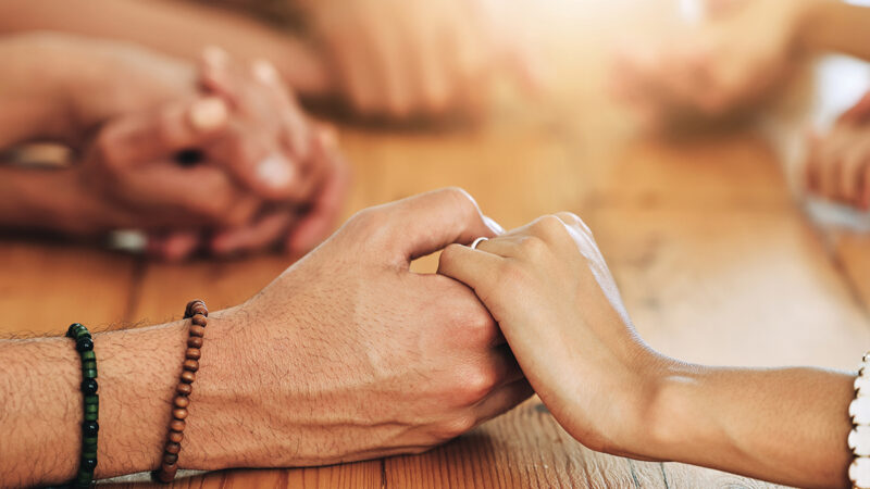 Holding hands, family and support by group of people together in unity, spiritual and faith in God and gratitude. Closeup, Solidarity, religion and hope in a home for worship due to grief